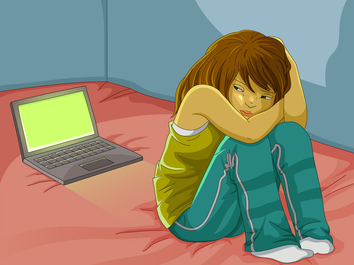 sad girl sitting alone next to her open laptop